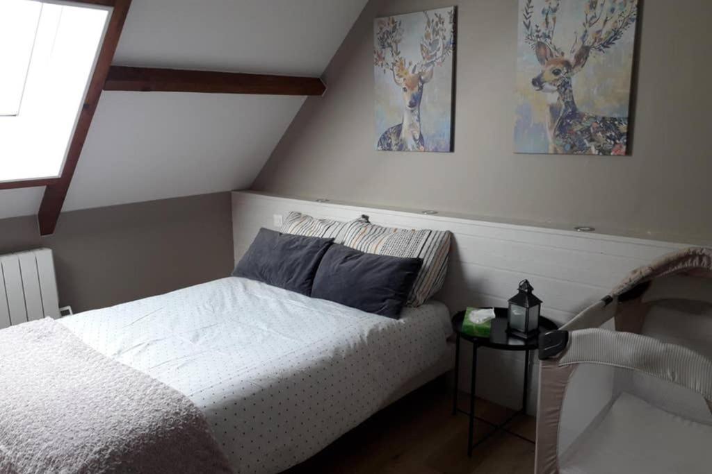 ein Schlafzimmer mit einem Bett und zwei Bildern an der Wand in der Unterkunft LES ENFANTS DU MOULIN in Saint-Léger-sur-Bresle