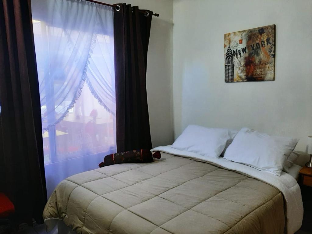 a bedroom with a bed and a window with avertisement at Hostal Los Castaños in Viña del Mar