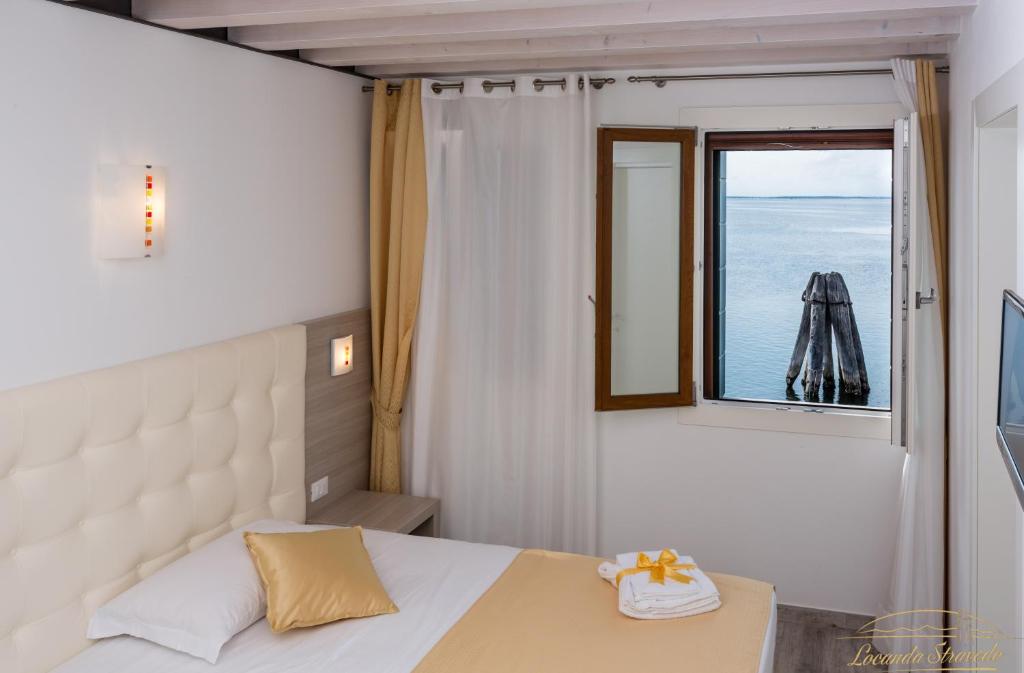 a bedroom with a bed and a window with the ocean at Locanda Stravedo in Pellestrina