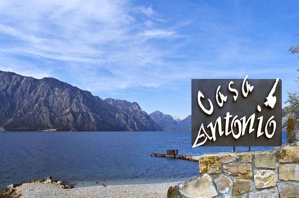 Una señal para un lago con montañas en el fondo en Casa Antonio en Malcesine