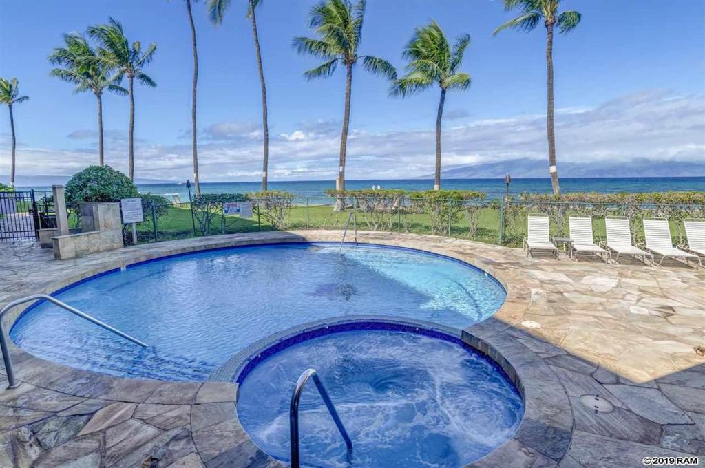 a swimming pool with palm trees and the ocean at Lahaina Wonderful Condos - Paki Maui in Lahaina
