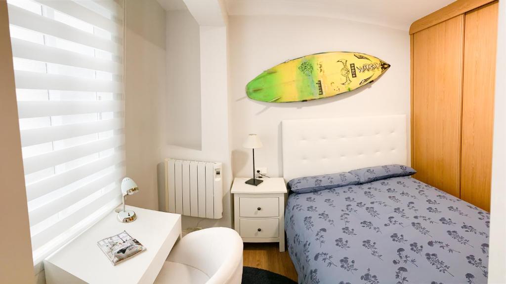 a bedroom with a bed and a surfboard hanging on the wall at Surf Home, Orzán in A Coruña