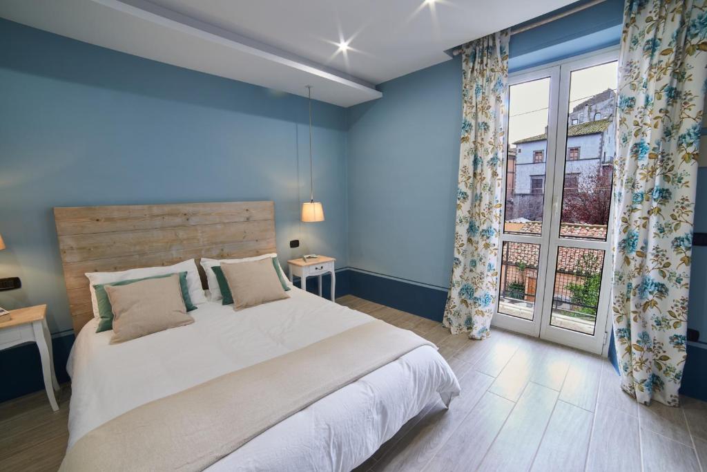 een blauwe slaapkamer met een groot bed en een raam bij AL22 di piazza del Gesù in Viterbo
