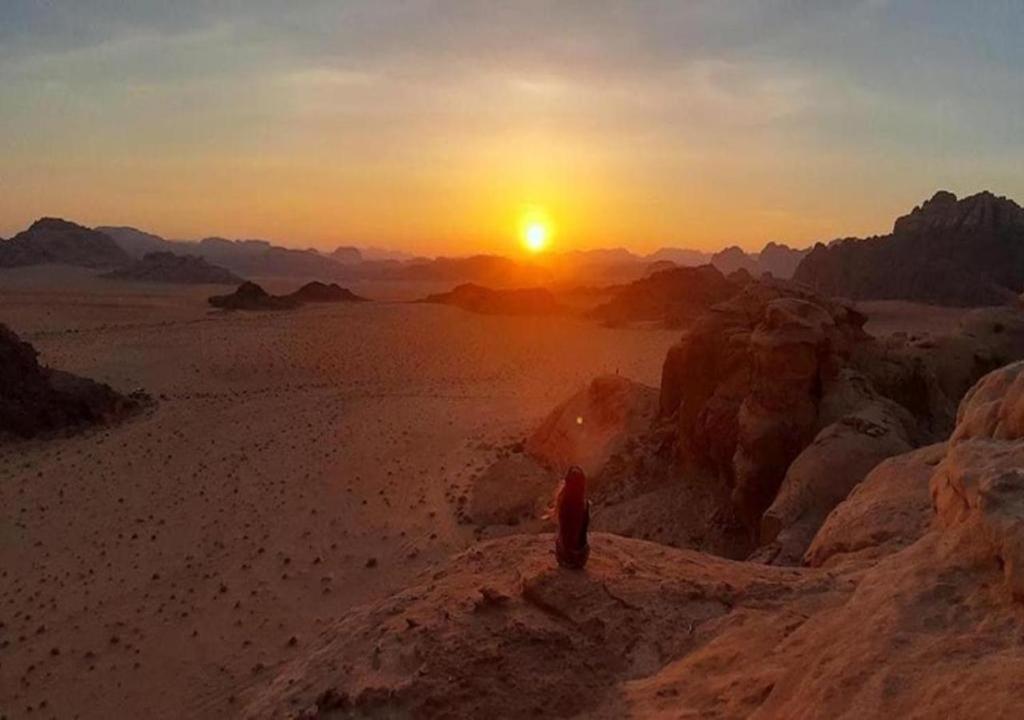 una persona de pie en el desierto viendo la puesta de sol en Wadi Rum en Wadi Rum