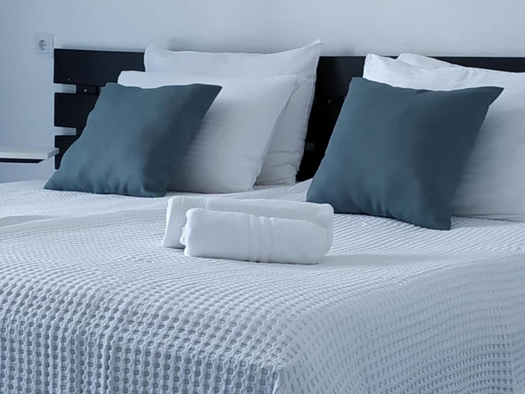 Una cama blanca con almohadas azules y blancas. en Hotel Kolkhi, en Gonio