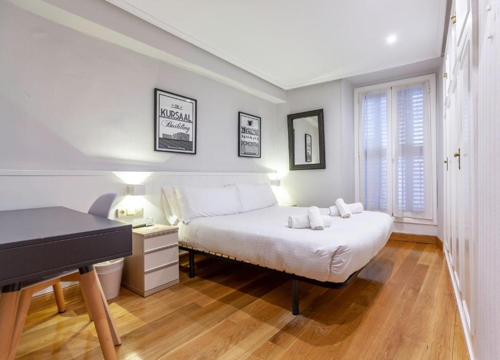 ein Schlafzimmer mit einem weißen Bett und einem Klavier in der Unterkunft Pension Larrea in San Sebastián