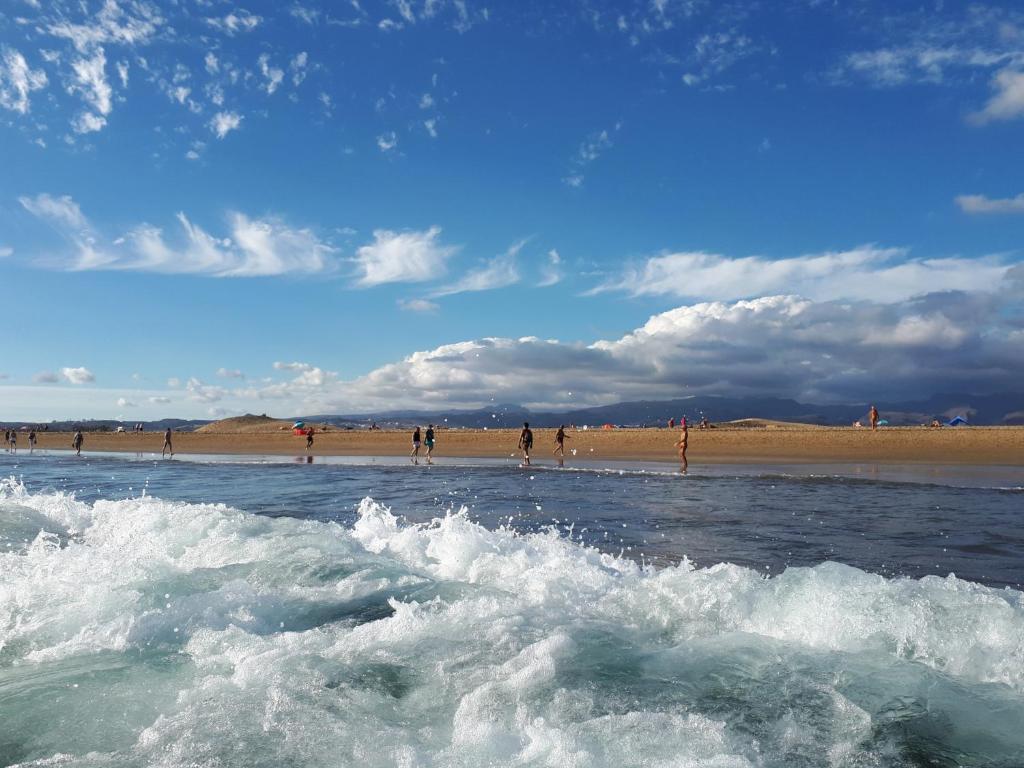 a group of people standing in the water at the beach at Taidia Sunset View in Playa del Ingles