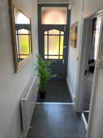 a hallway with a black door and a potted plant at Bentley House with en-suites in Crewe
