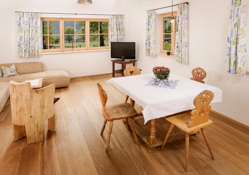 een woonkamer met een tafel en stoelen en een bank bij Ferienwohnung Glaserhäusl Seeblick in Schliersee