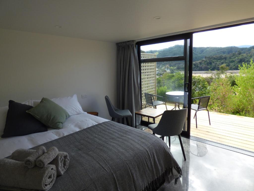a bedroom with a bed and a balcony with a table and chairs at Kaiteriteri Abel Tasman Inlet Views in Kaiteriteri