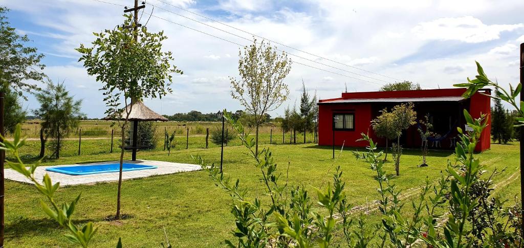 a small red house with a pool in a yard at La Maina Uribe in Uribelarrea