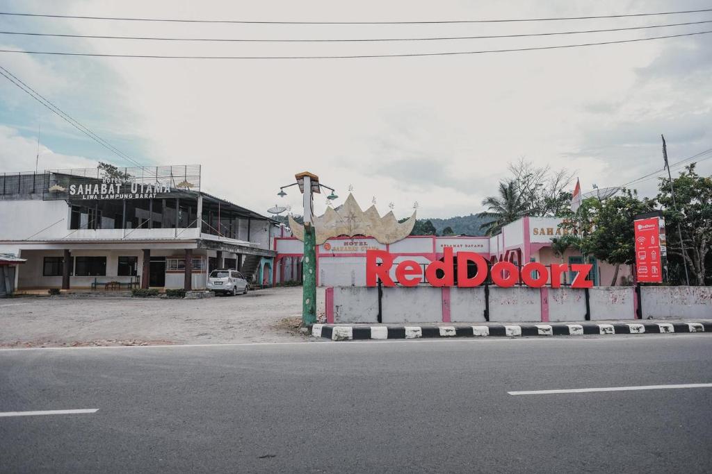 una strada in una città con un cartello che legge la porta rossa di RedDoorz Syariah near Kebun Raya Liwa a Lampung