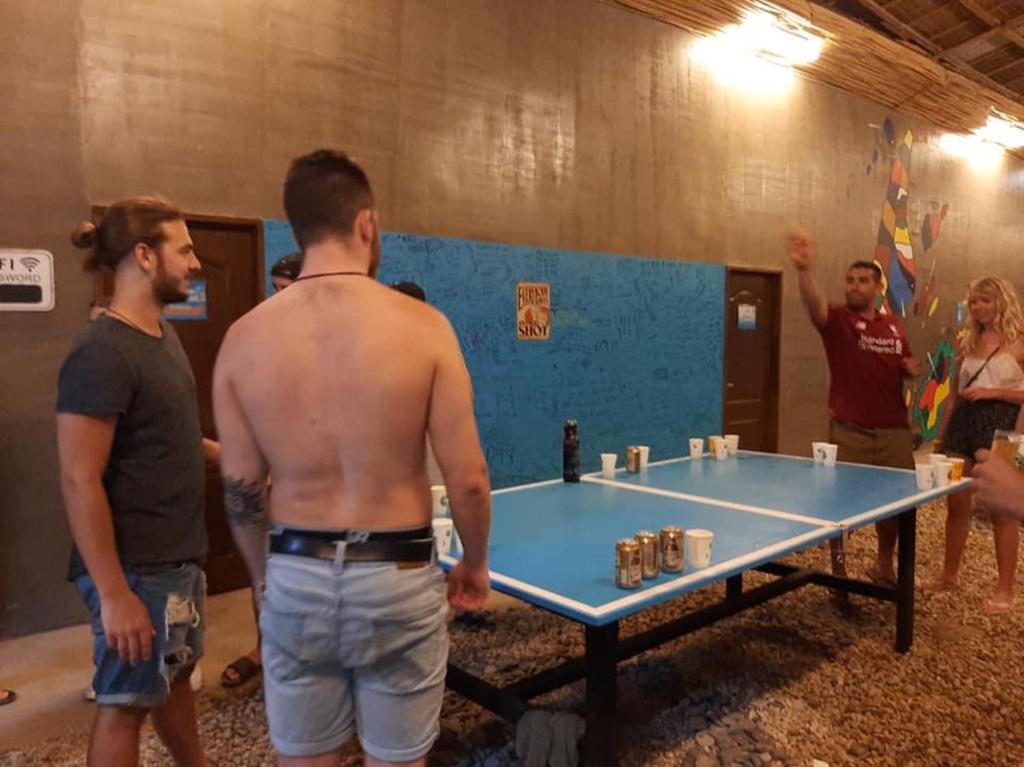 a shirtless man standing next to a ping pong table at Big Paul Hostel in El Nido