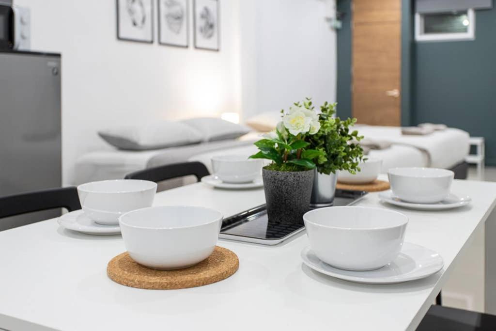 a table with white bowls and plates and flowers on it at P1 Silom Pan large room full kitchen WIFI 4-6pax in Bangkok