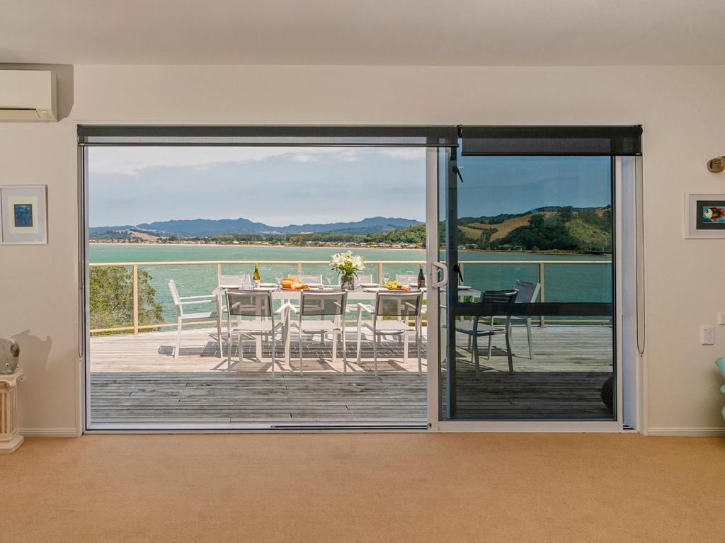 a sliding glass door leading to a patio with a table at Seaview Serenity- Whitianga Holiday Home in Whitianga