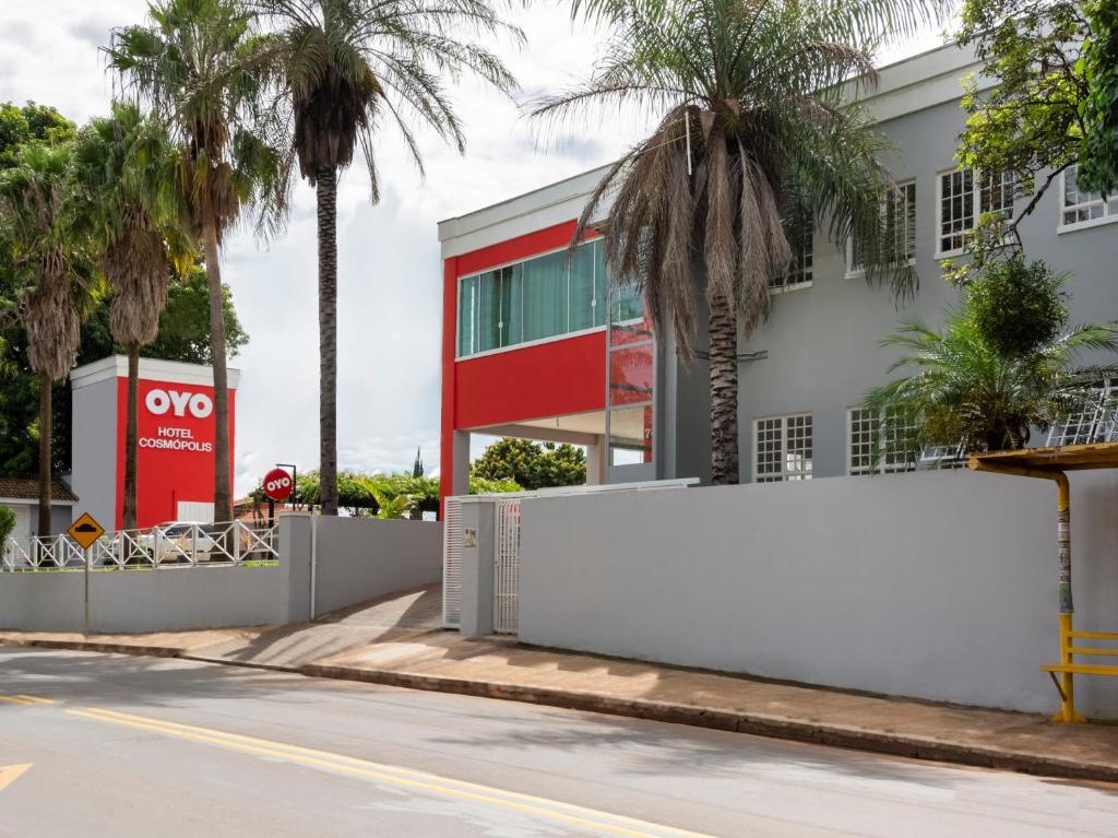 una valla blanca frente a un edificio con palmeras en OYO Hotel Cosmópolis, Sao Paulo, en Cosmópolis