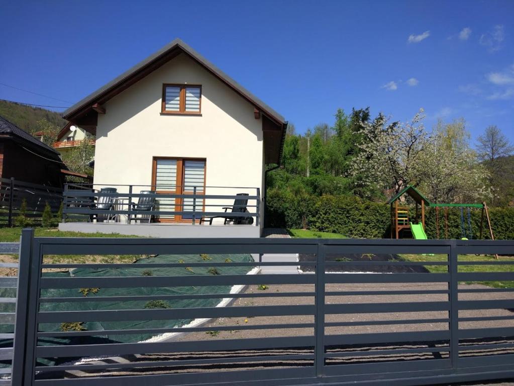 a white house with a fence in front of it at Domek Pod Górą Żar in Międzybrodzie Żywieckie