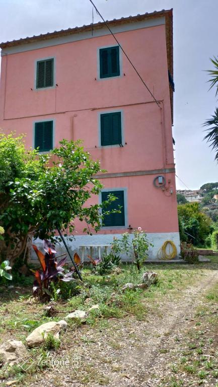 a pink house with windows on a dirt road at Appartamentino Bianco in Rio Marina