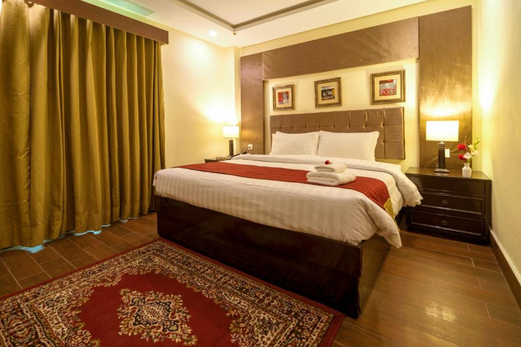 ファイサラーバードにあるHotel One Faisalabadのベッドルーム1室(大型ベッド1台、赤いラグ付)