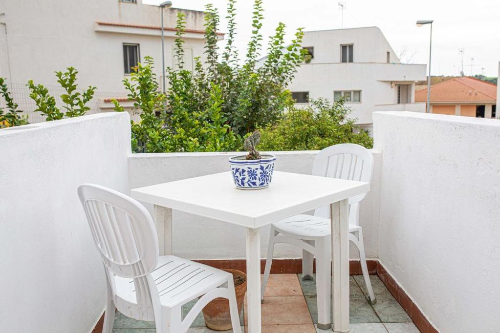 a white table with two chairs and a potted plant on a balcony at Pink liberty house in Santa Croce Camerina