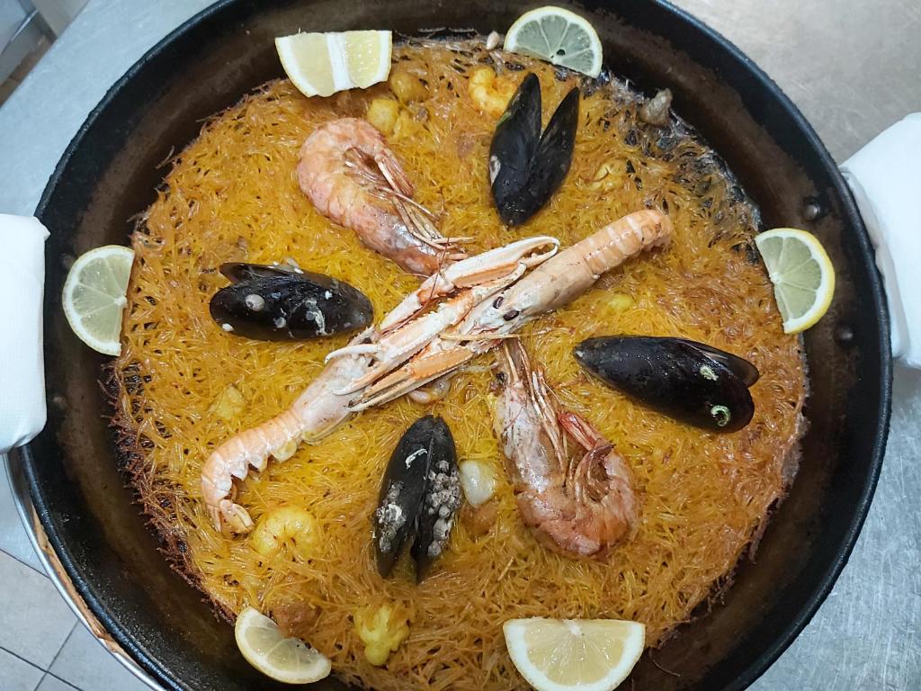 a plate of food with shrimp and mussels in a pan at Hotel Playa Canet in Canet de Berenguer