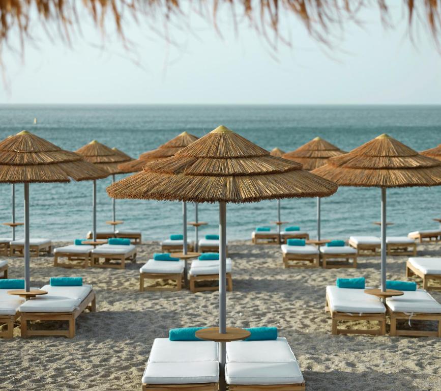 a bunch of chairs and umbrellas on a beach at Mitsis Selection Blue Domes in Kardamaina
