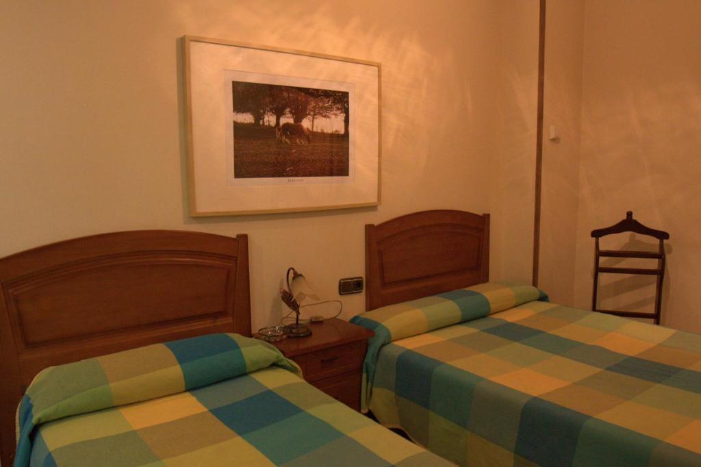 1 dormitorio con 2 camas y una foto en la pared en Hostal Rural Elosta en Lekunberri