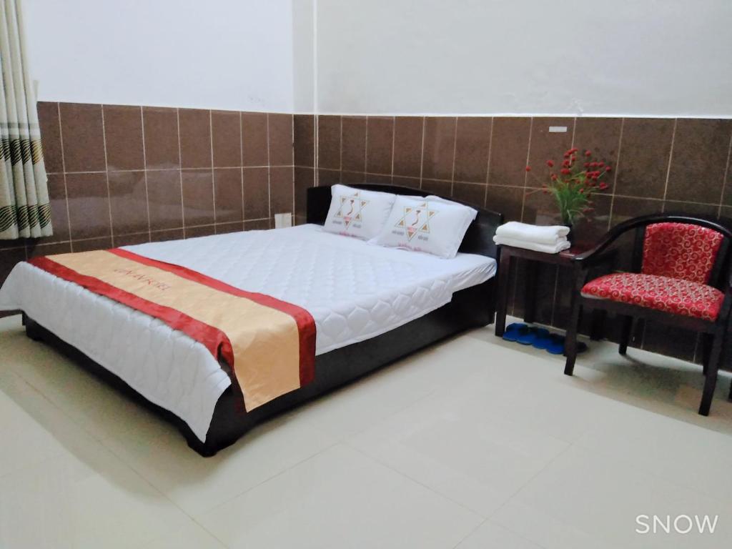 a bedroom with a bed and a chair at Kiến An Hotel Cần Thơ in Can Tho
