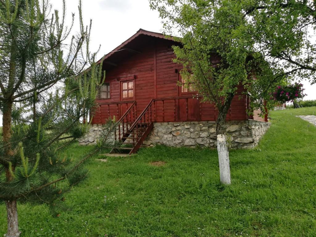 a log cabin with a stone wall and a tree at Pensiunea Gernik 100 in Gârnic