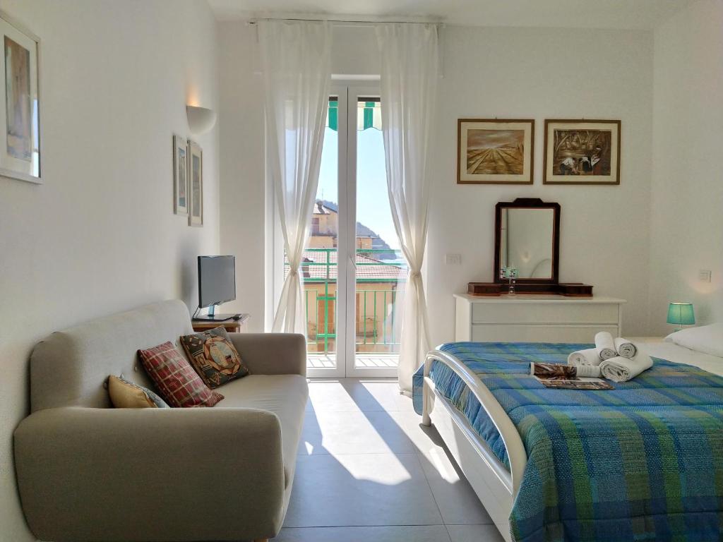 sypialnia z łóżkiem, kanapą i oknem w obiekcie Giulia & Giovanna Apartments w mieście Levanto