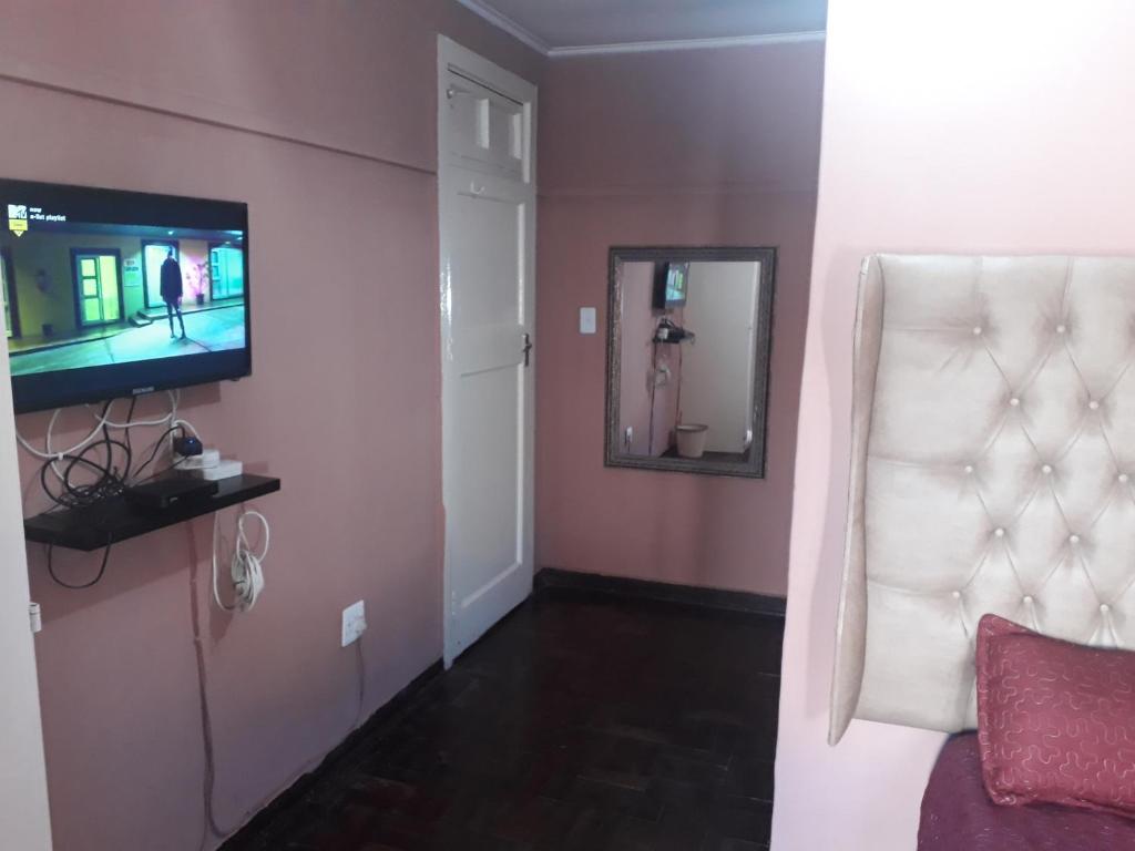 Zimmer mit einem Bett, einem TV und einem Spiegel in der Unterkunft Coolden guesthouse in Vanderbijlpark