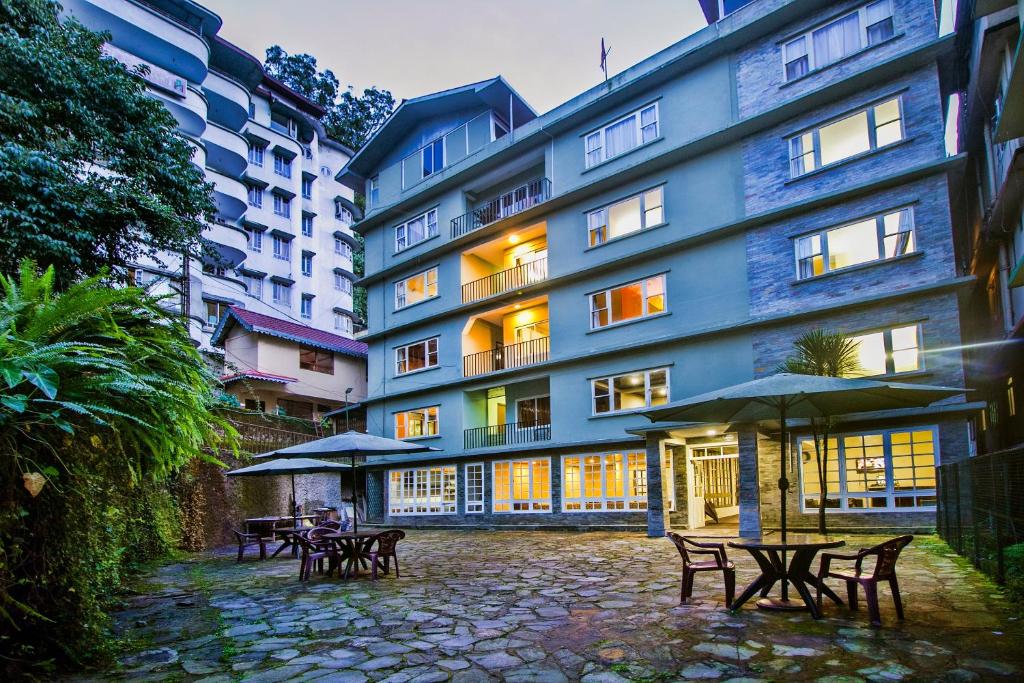 a group of tables and umbrellas in front of a building at FabHotel Oak Ridge Retreat I in Gangtok