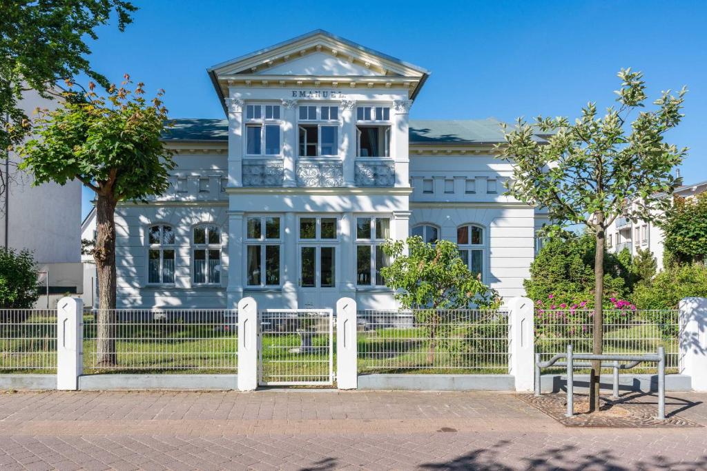 ein blaues Haus mit einem weißen Zaun davor in der Unterkunft Villa Emanuel mit Meerblick in Ahlbeck