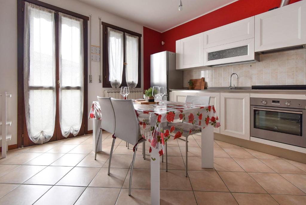 una cucina con tavolo, sedie e pareti rosse di Welc-om Romantic Flat a Vigonovo