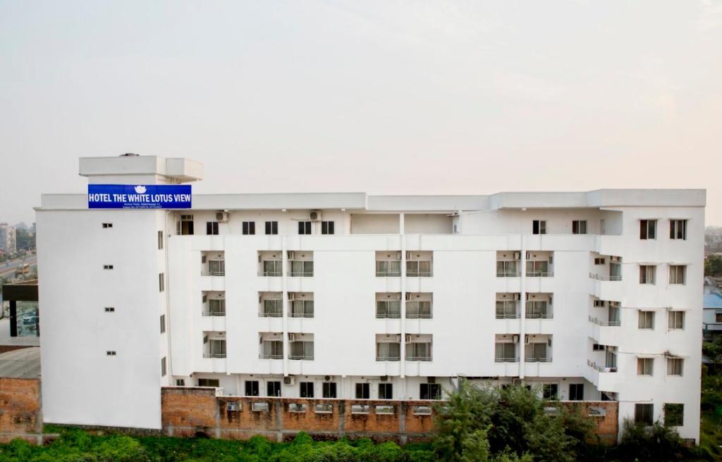 Un bâtiment blanc avec un panneau bleu au-dessus dans l'établissement Hotel The White Lotus View Pvt Ltd, à Siddharthanagar
