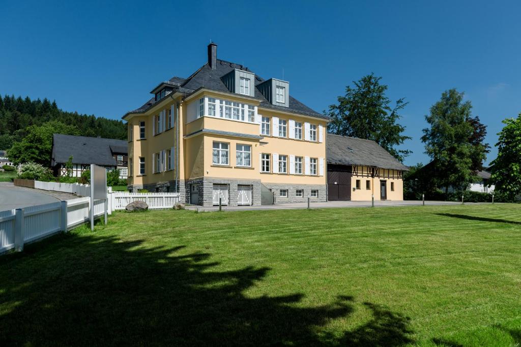 a large yellow house with a large grass field at Residenz Itterbach in Willingen