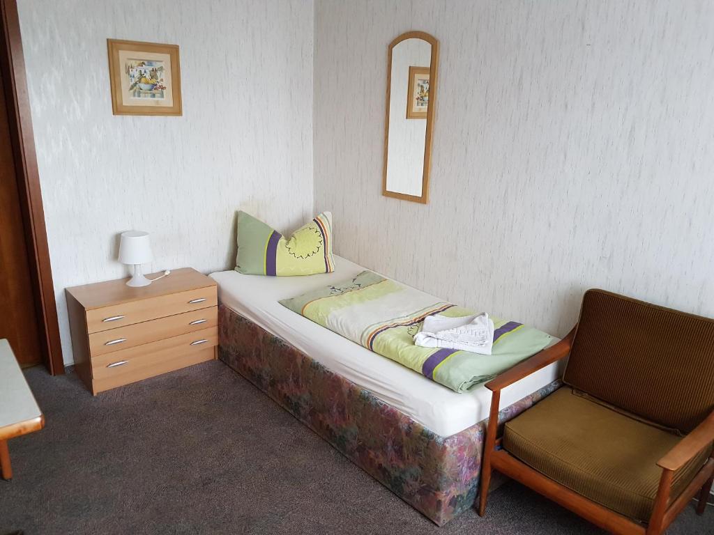 a small bed and a chair in a room at Hotel Arkona in Genthin
