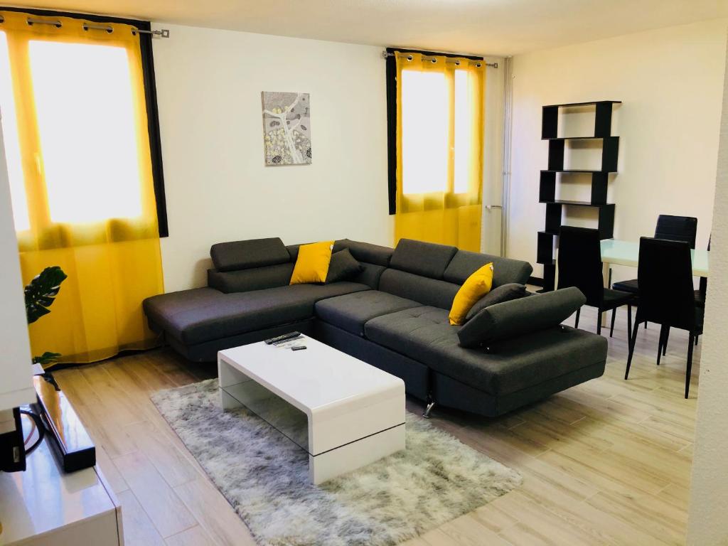 sala de estar con sofá negro y almohadas amarillas en Bella vita en Thonon-les-Bains