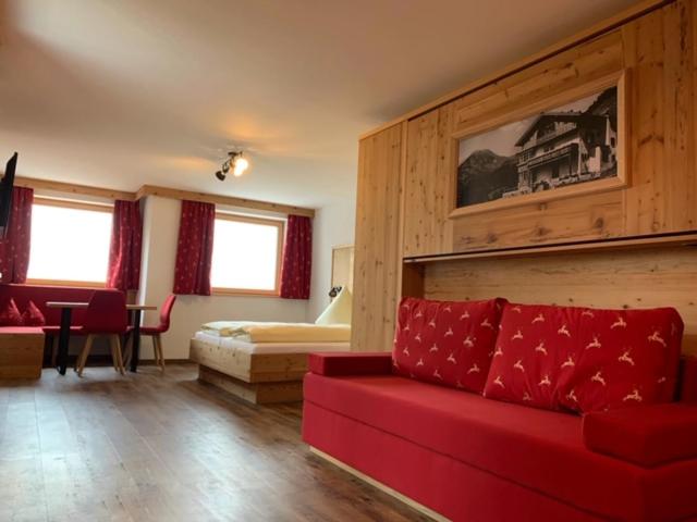 a living room with a red couch and a bedroom at Berggasthof Hummelei in Oberaudorf