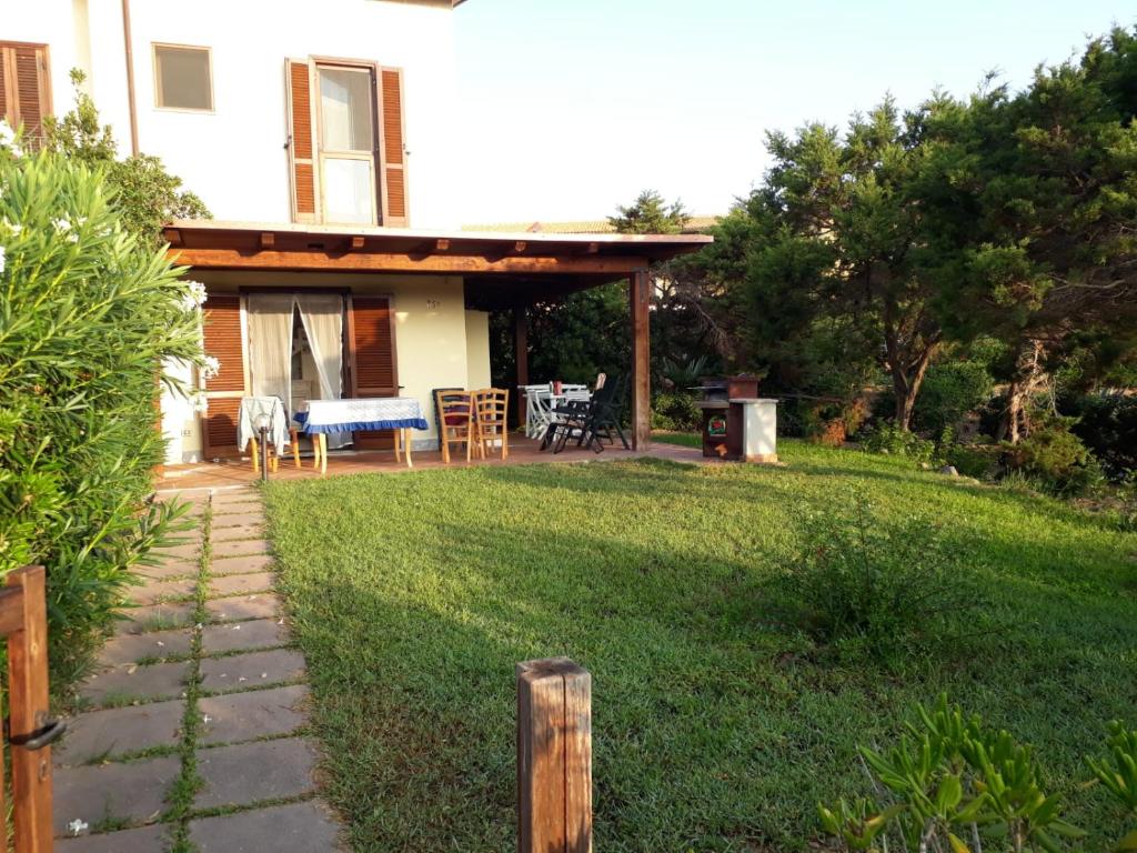 un cortile con una casa e un patio con sedie di Baia delle Mimose Garden a Badesi