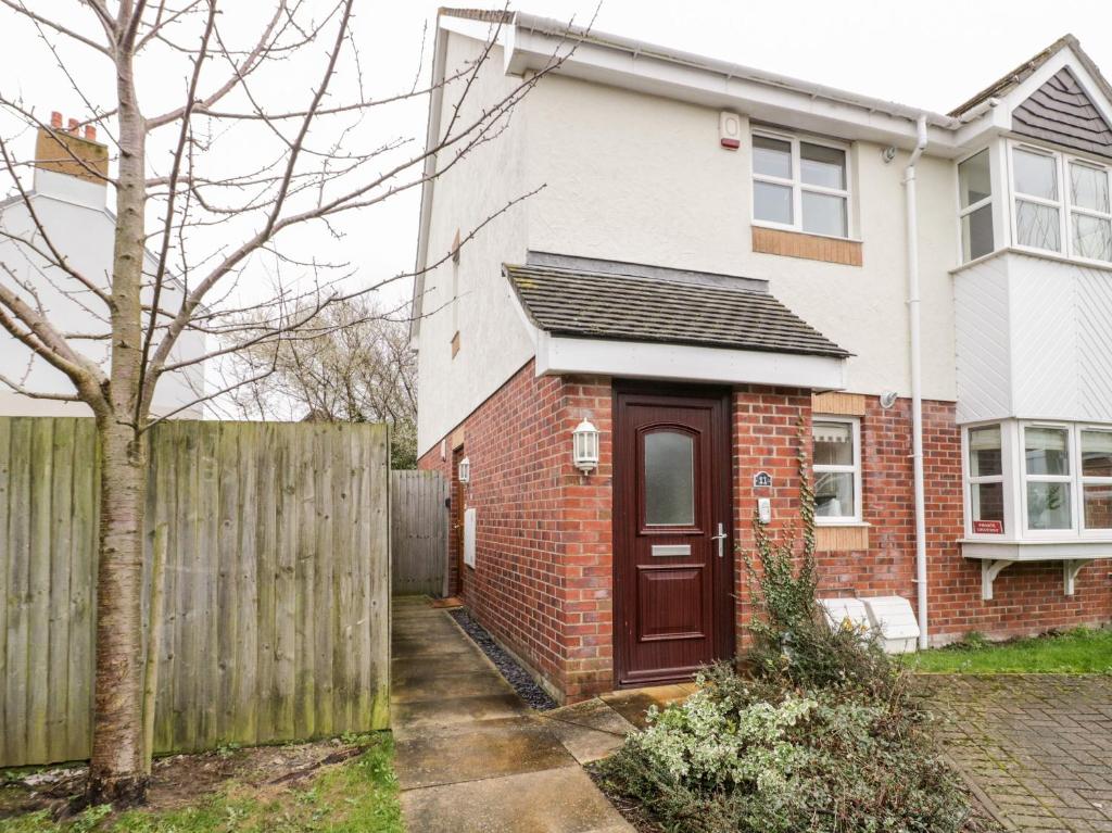 a red brick house with a wooden fence at 10 The Orchard in Colwyn Bay