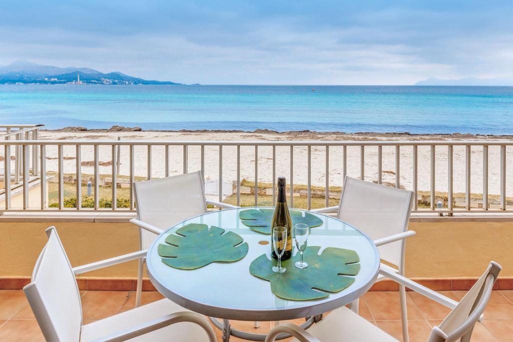 een tafel met een fles wijn en stoelen op het strand bij Apartamento Buganvilia sea in Alcudia