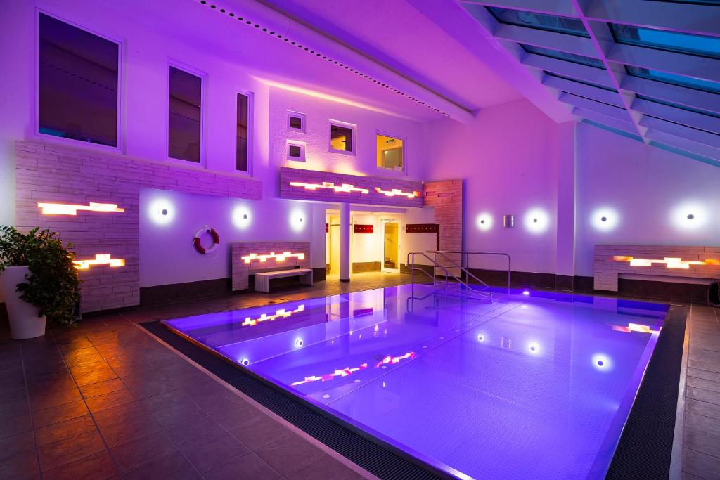 a large swimming pool in a building with purple lighting at Bio- und Wellnesshotel Alpenblick in Höchenschwand