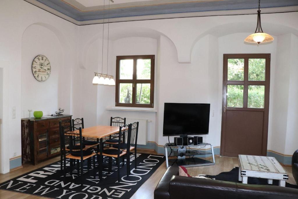 a living room with a table and a tv at Ferienwohnung-im-Pfarrhaus in Müglitztal