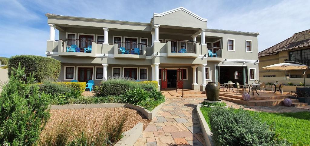 a large white house with a patio in front of it at The Mandyville Jeffreys Bay in Jeffreys Bay