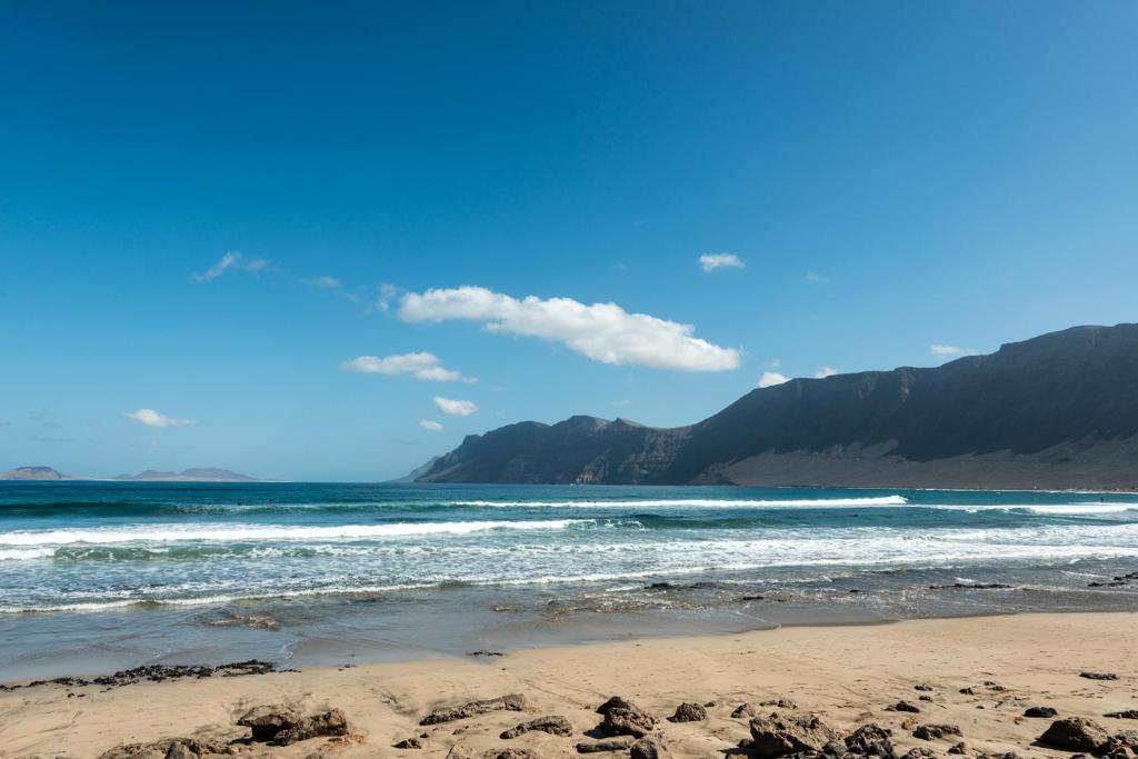 a beach with the ocean and mountains in the background at Modern beach house in Famara in Famara