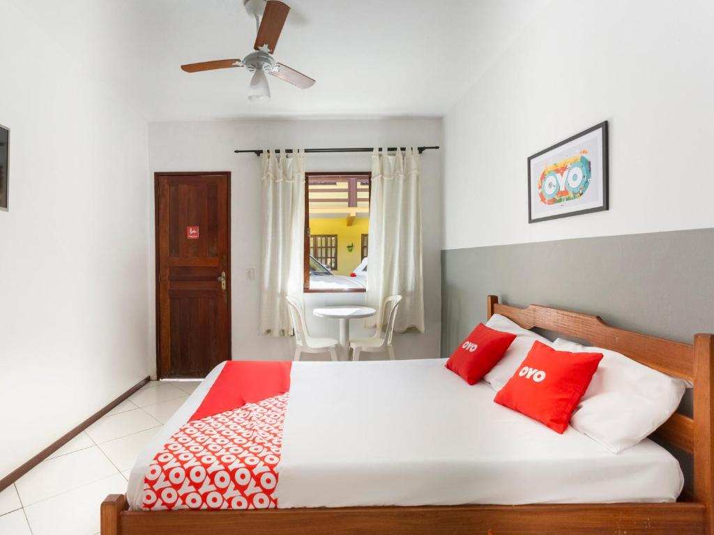 a bedroom with a bed with red and white pillows at OYO Hotel Recanto Do Alto, Teresópolis in Teresópolis