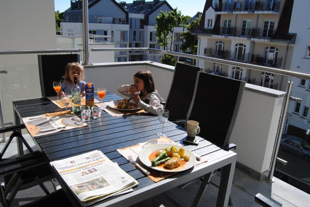 dos niños sentados en una mesa comiendo comida en un balcón en Stella Baltic 39 en Świnoujście