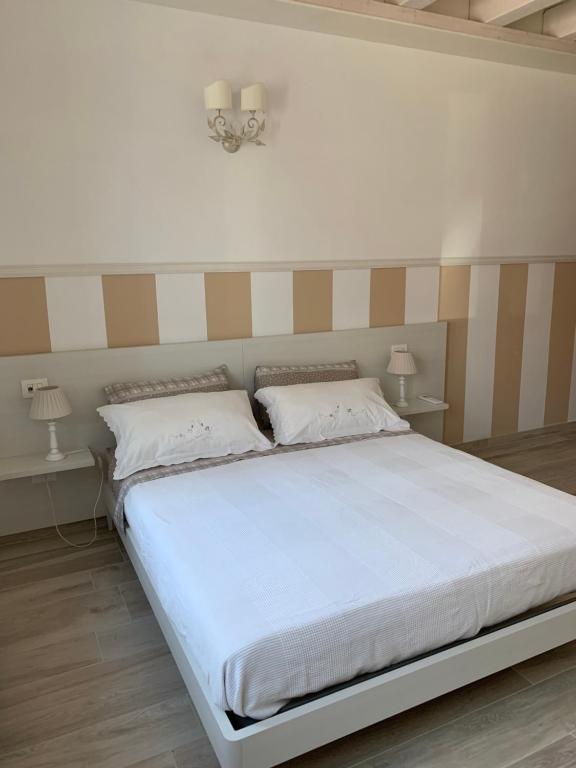 a bedroom with a large white bed with two lamps at B&B Nonna Teresa in Roverbella