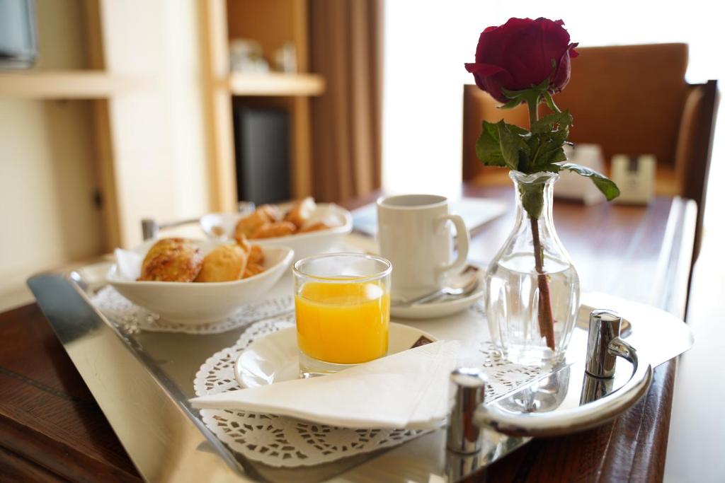 a table with a vase of flowers and a vase of orange juice at Ajax Hotel in Limassol